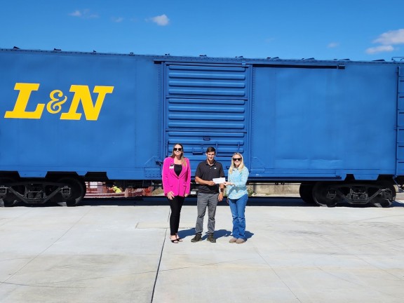 Sadie Miskuf (left), Regional Main Street Director of the Magnificent Monon South Main Street Program, and Blaine Parker (right), Director of Entrepreneurship and Small Business Support for Radius Indiana, present Dalton Morris (center) with prize check.